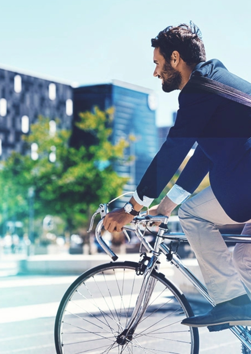 Ein Mann auf einem Fahrrad fährt auf einem Rennrad zur Arbeit. Das Bild geht auf die Vision von autofreien Innenstädten ein.